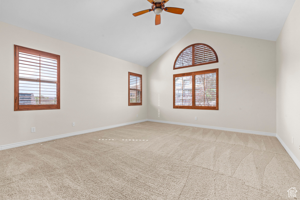 Carpeted spare room with lofted ceiling and ceiling fan