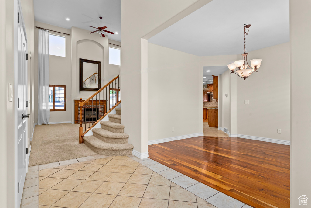 Foyer featuring a healthy amount of sunlight, ceiling fan with notable chandelier, light wood-type flooring, and a brick fireplace