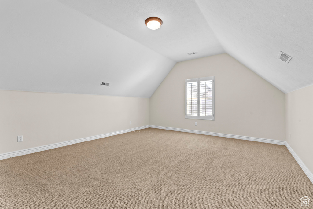 Bonus room with lofted ceiling and light carpet