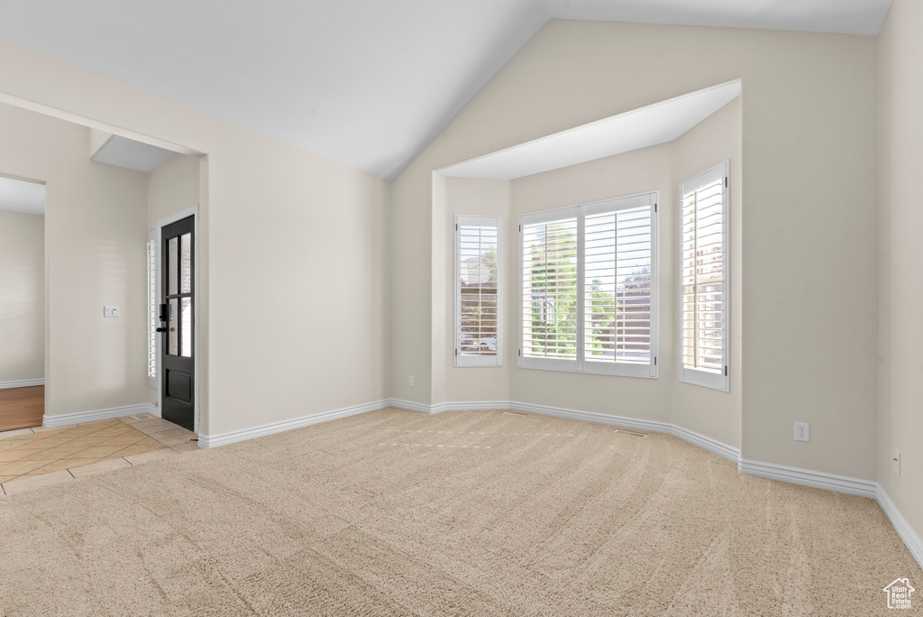 Unfurnished room with light carpet and lofted ceiling