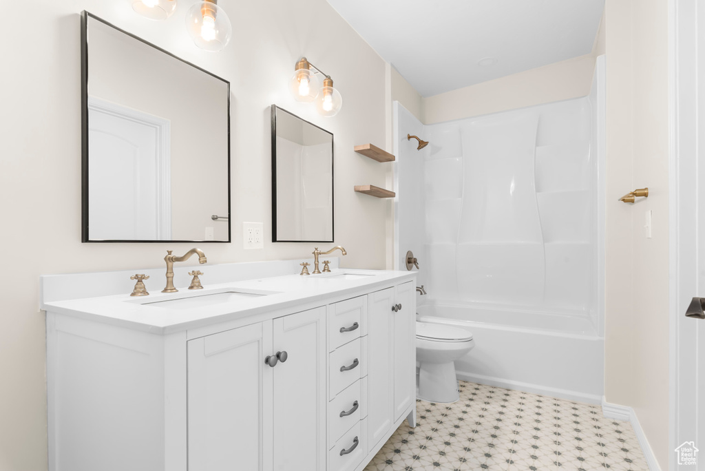 Full bathroom with vanity, toilet, tile patterned floors, and washtub / shower combination