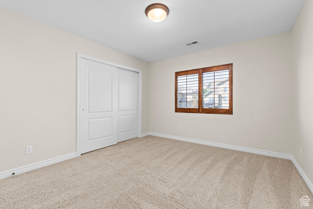 Unfurnished bedroom with light colored carpet and a closet