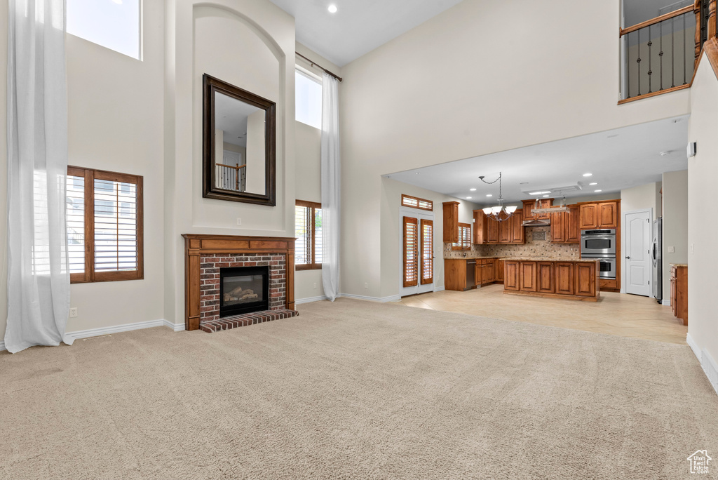 Carpeted living room with a wealth of natural light, a fireplace, and a towering ceiling