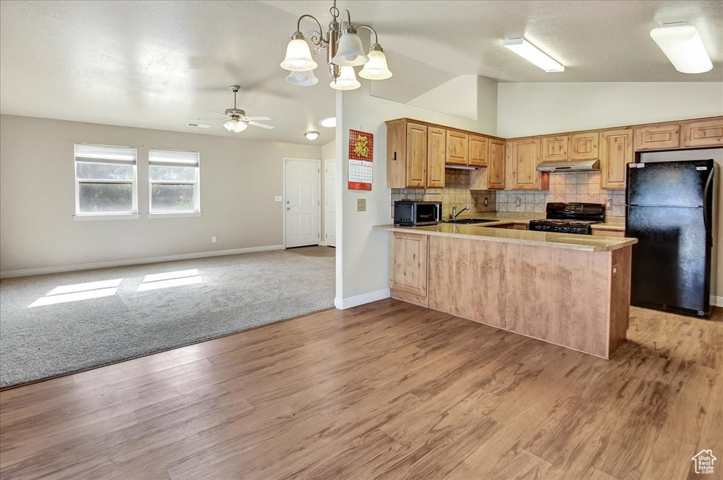 Kitchen featuring ceiling fan with notable chandelier, light colored carpet, sink, black appliances, and kitchen peninsula