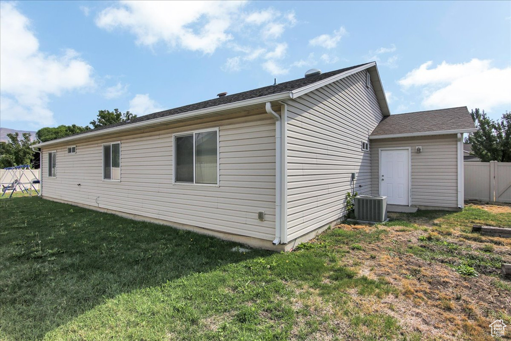 View of side of home with a yard and central AC unit