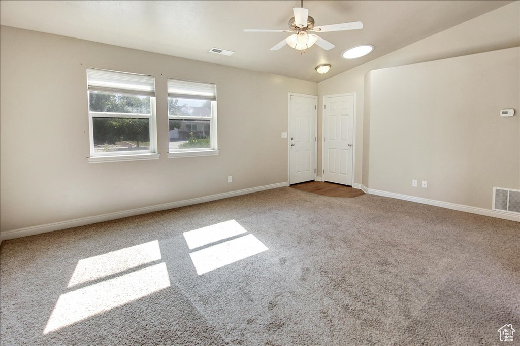 Empty room featuring lofted ceiling, ceiling fan, and carpet