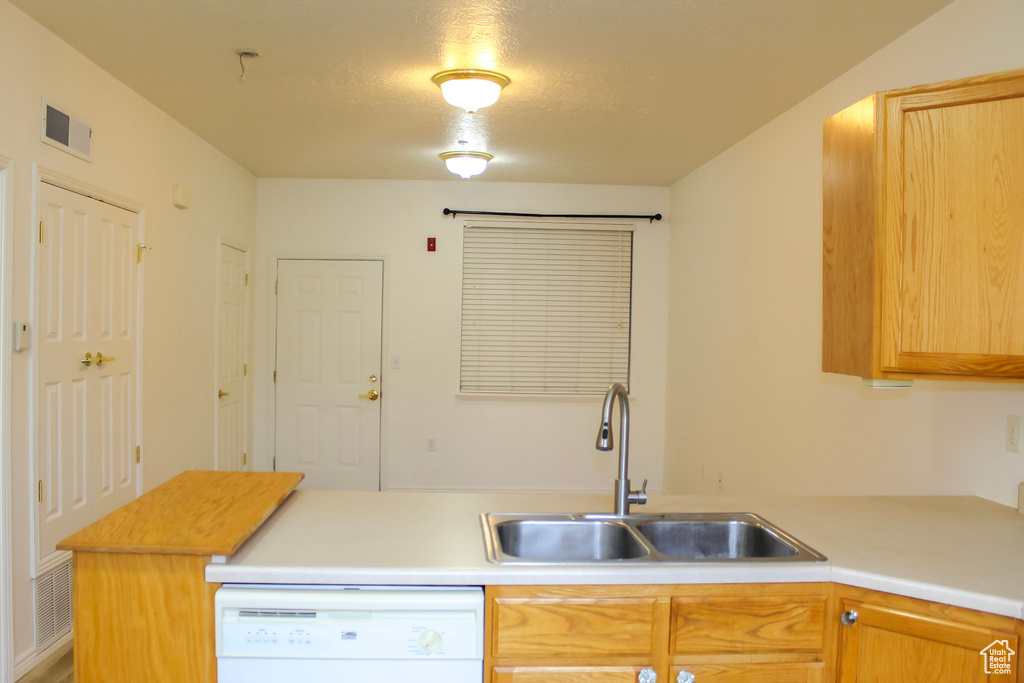 Kitchen with a textured ceiling, sink, and white dishwasher