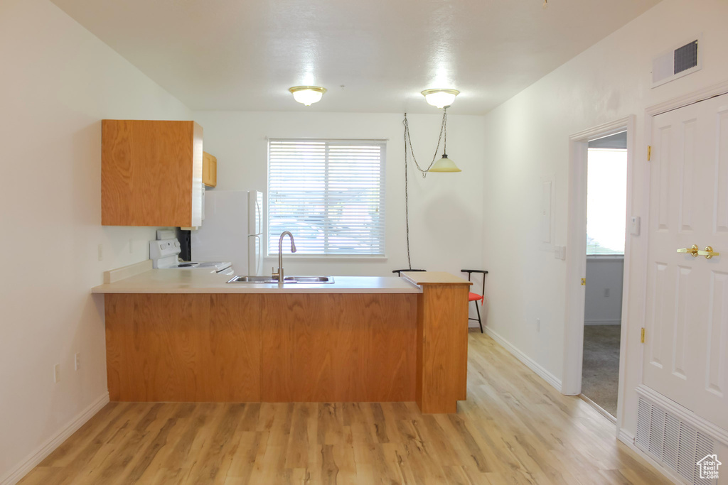 Kitchen featuring sink, light hardwood / wood-style flooring, kitchen peninsula, and range