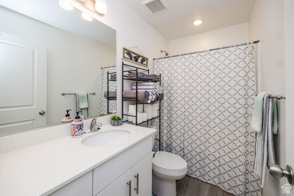 Bathroom with a shower with shower curtain, vanity, toilet, and wood-type flooring