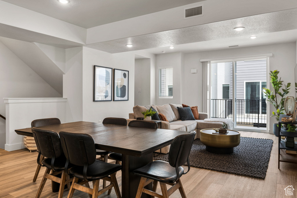 Dining space featuring plenty of natural light, a textured ceiling, and light hardwood / wood-style flooring