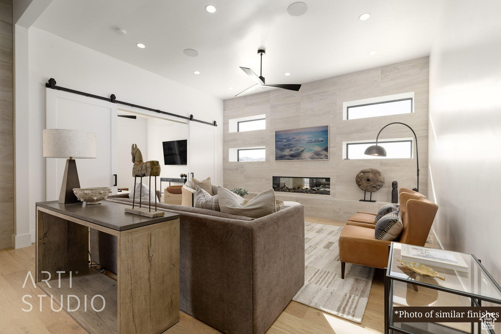 Living room featuring a barn door, tile walls, a multi sided fireplace, and light hardwood / wood-style flooring