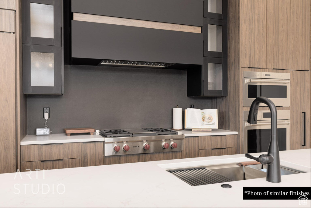 Kitchen with ventilation hood, stainless steel appliances, and sink