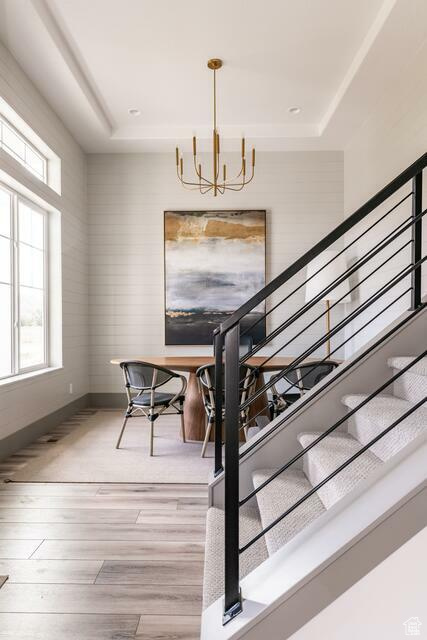 Staircase featuring a notable chandelier, wood-type flooring, and a tray ceiling