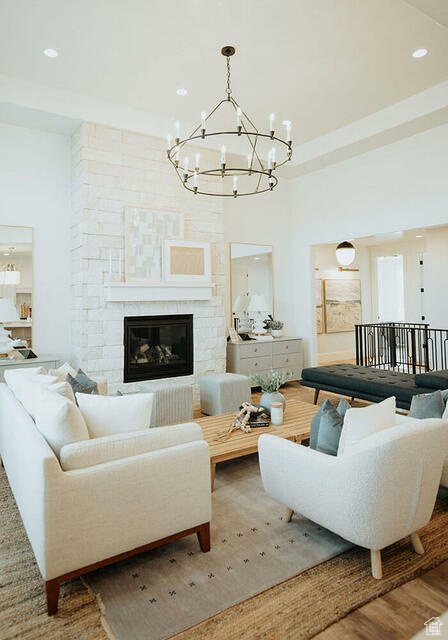 Living room featuring an inviting chandelier, a high ceiling, hardwood / wood-style floors, and a stone fireplace