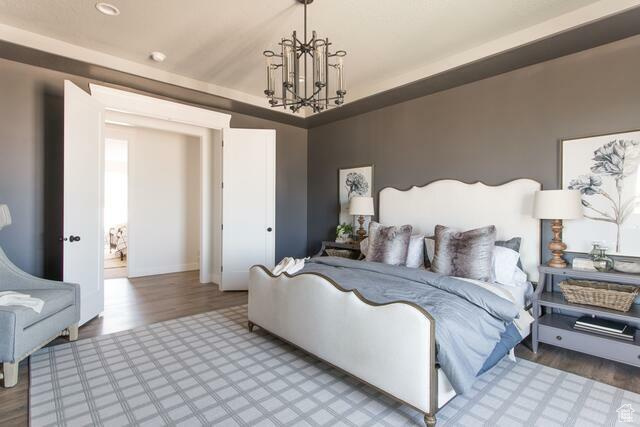 Bedroom with hardwood / wood-style floors and a notable chandelier