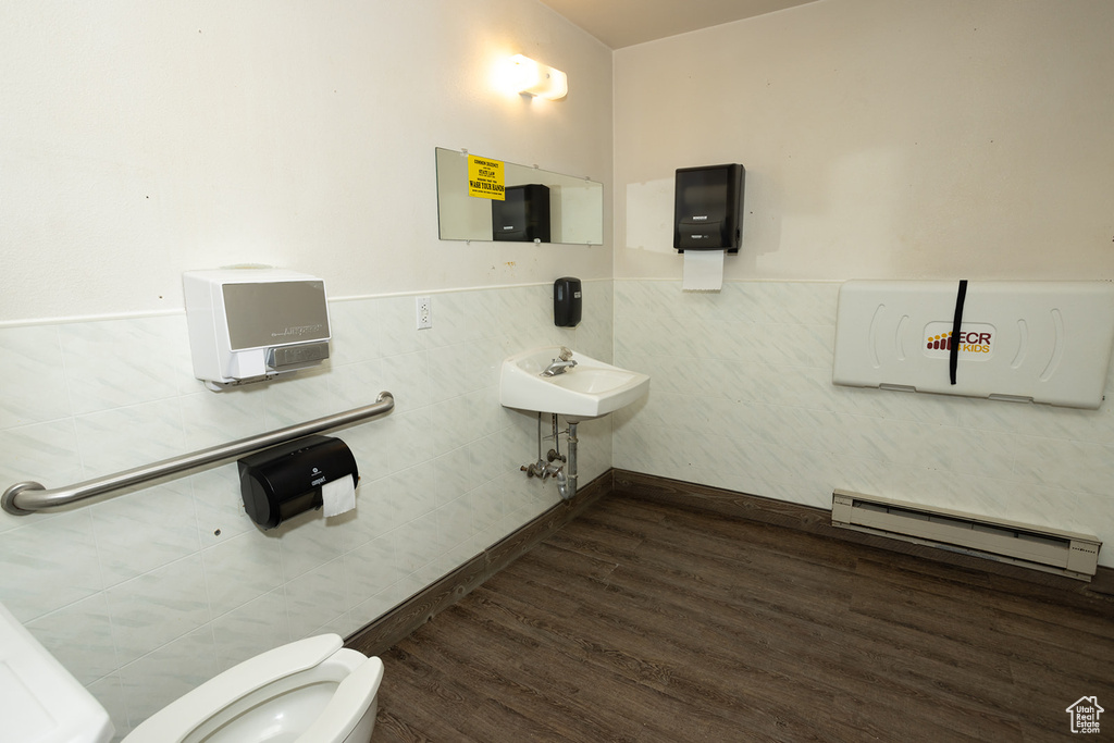 Bathroom with a baseboard radiator, toilet, hardwood / wood-style floors, and tile walls