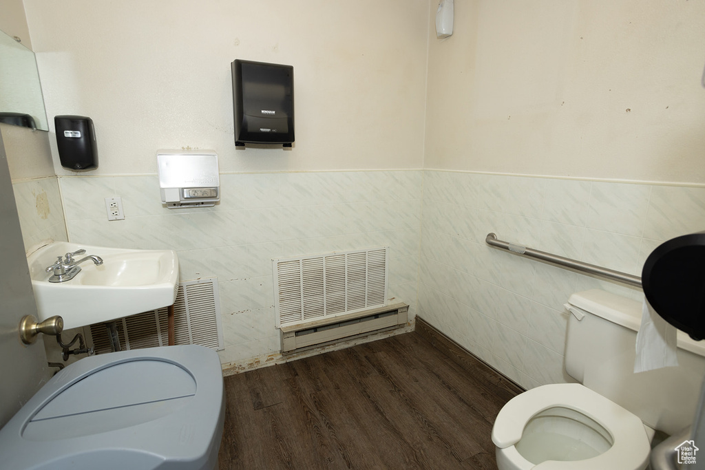 Bathroom with tile walls, wood-type flooring, toilet, and sink