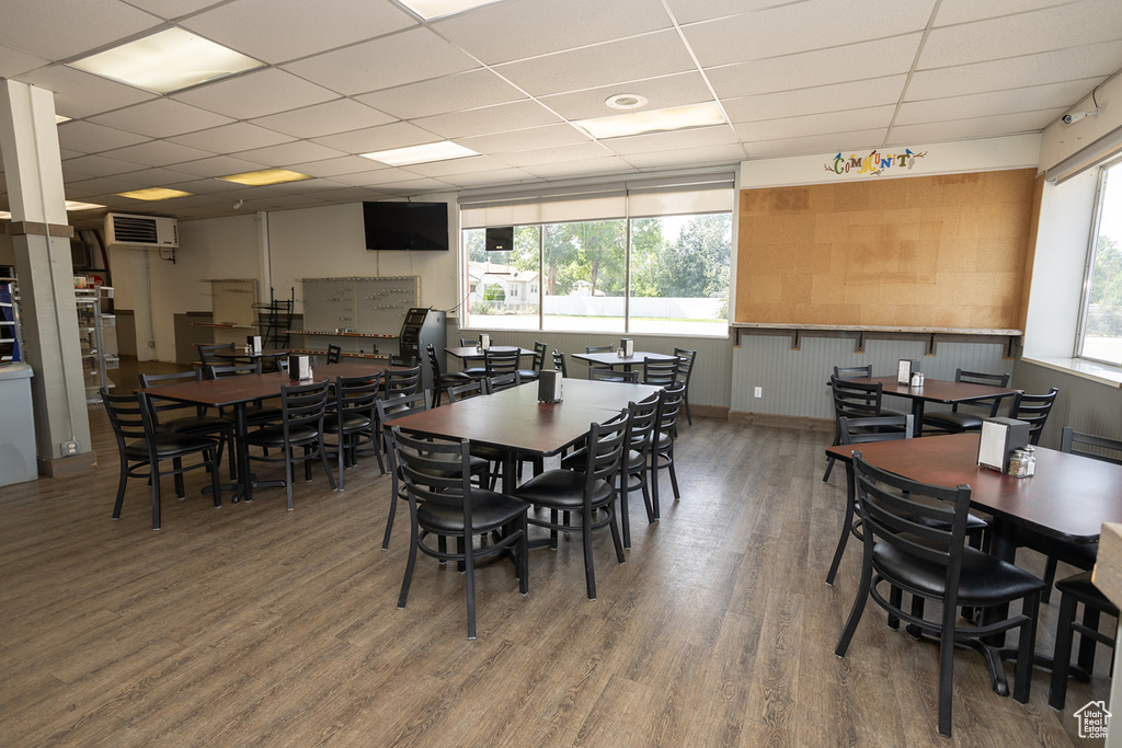 Dining space with hardwood / wood-style floors, a drop ceiling, and a healthy amount of sunlight