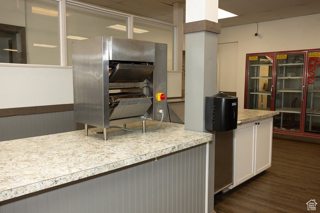 Kitchen with dark hardwood / wood-style flooring and white cabinetry