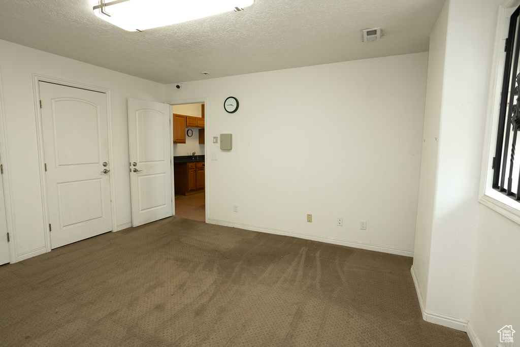 Empty room featuring a textured ceiling and carpet flooring