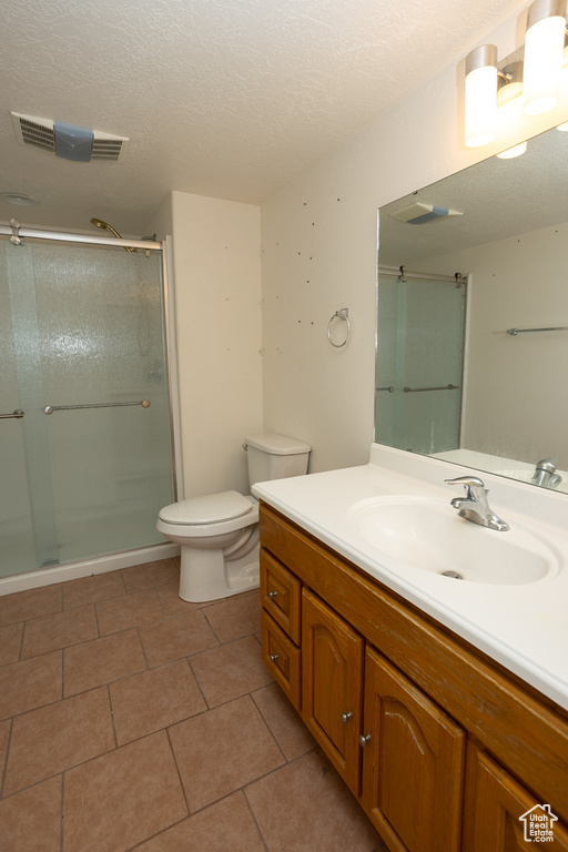 Bathroom with toilet, walk in shower, tile patterned flooring, vanity, and a textured ceiling