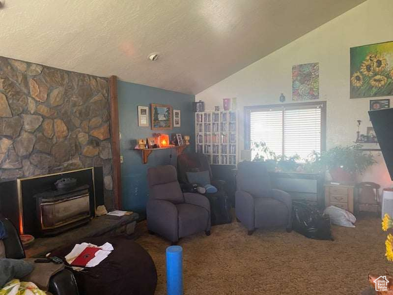 Carpeted living room with vaulted ceiling, a textured ceiling, and a stone fireplace