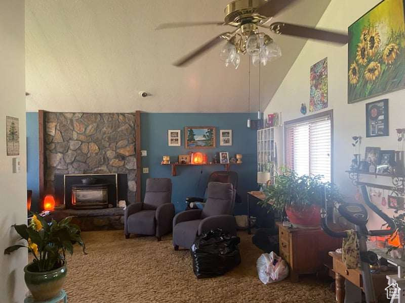 Interior space featuring high vaulted ceiling, ceiling fan, a fireplace, and carpet floors