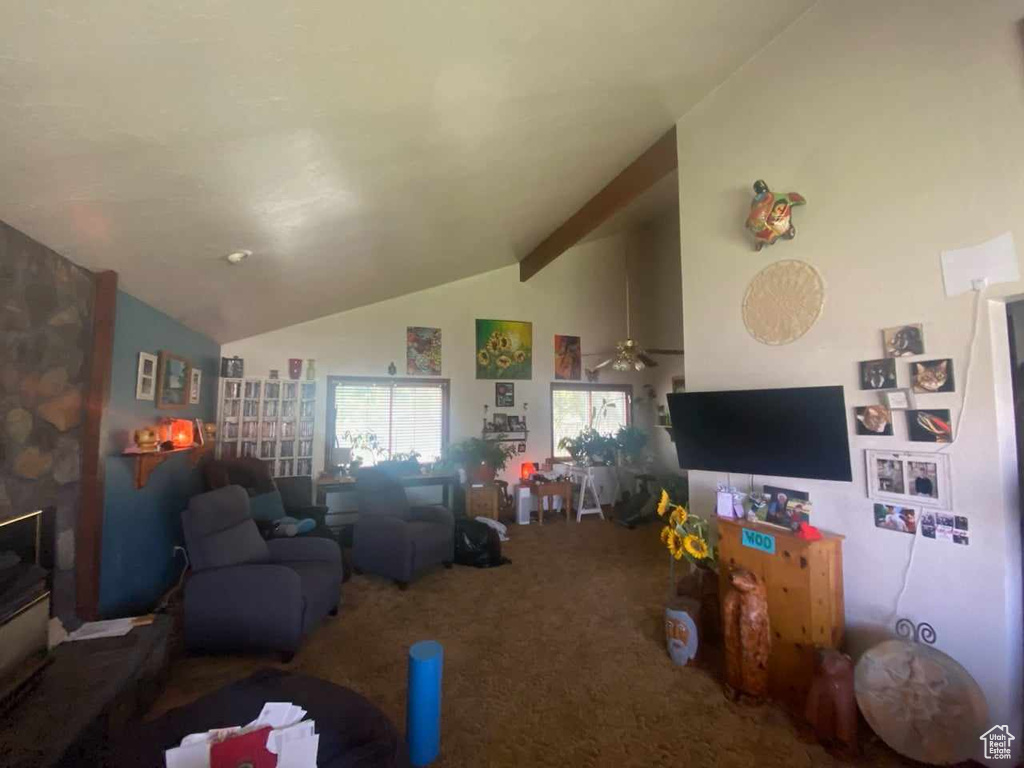 Carpeted living room with ceiling fan and lofted ceiling with beams