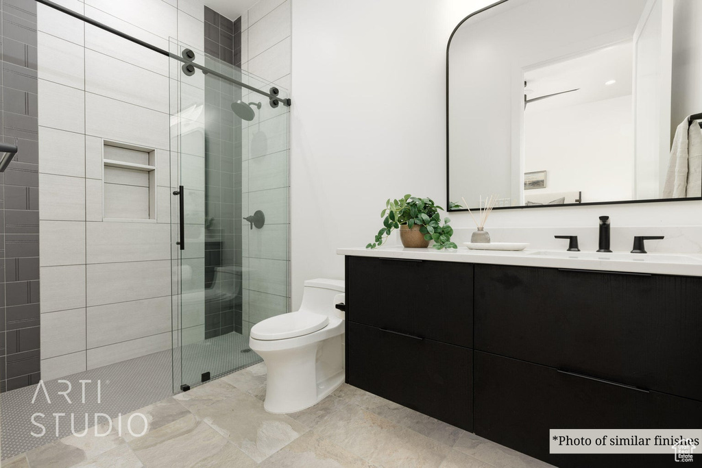 Bathroom featuring a shower with door, vanity, and toilet