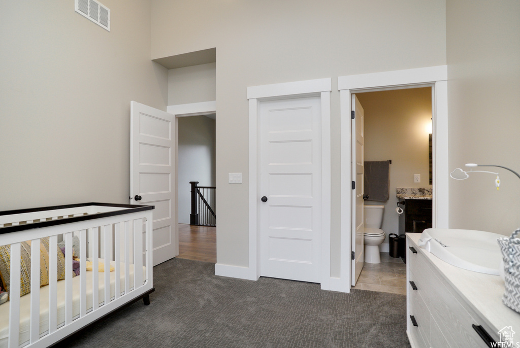 Carpeted bedroom featuring ensuite bath, sink, a closet, and a crib