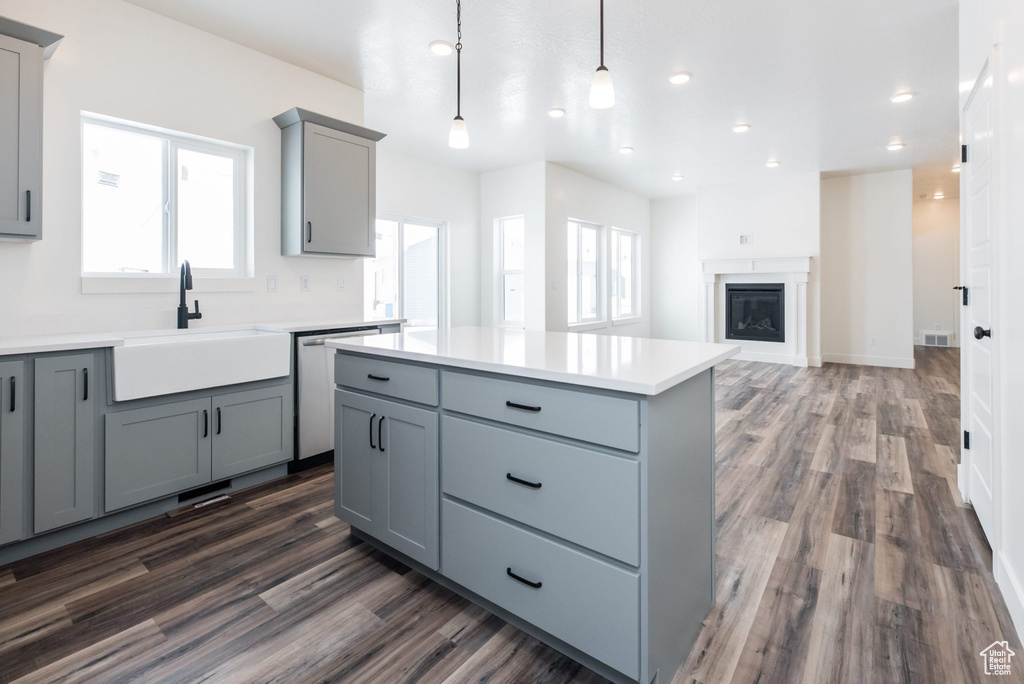 Kitchen with gray cabinets, a kitchen island, dark hardwood / wood-style flooring, and dishwasher