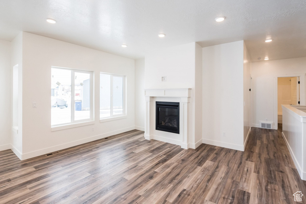 Unfurnished living room featuring dark hardwood / wood-style floors and a textured ceiling