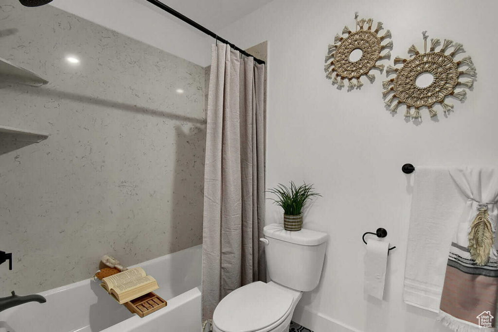 Bathroom featuring shower / bath combination with curtain and toilet