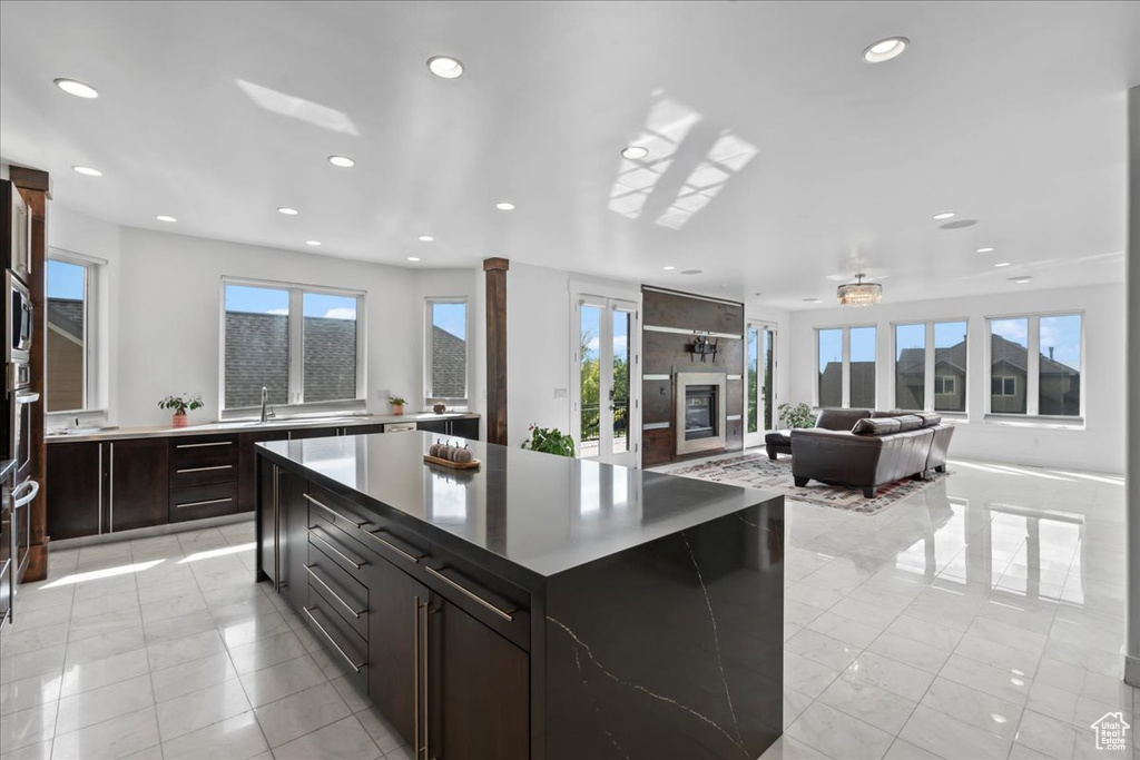 Kitchen with plenty of natural light, dark brown cabinetry, stainless steel microwave, and a kitchen island