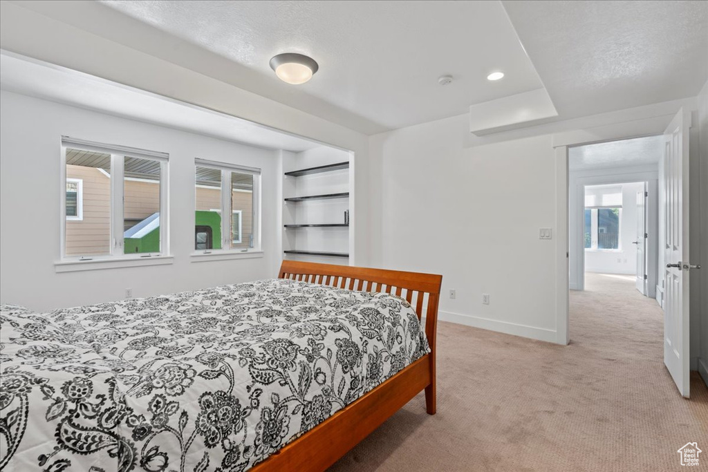 Bedroom with multiple windows, light colored carpet, and a textured ceiling