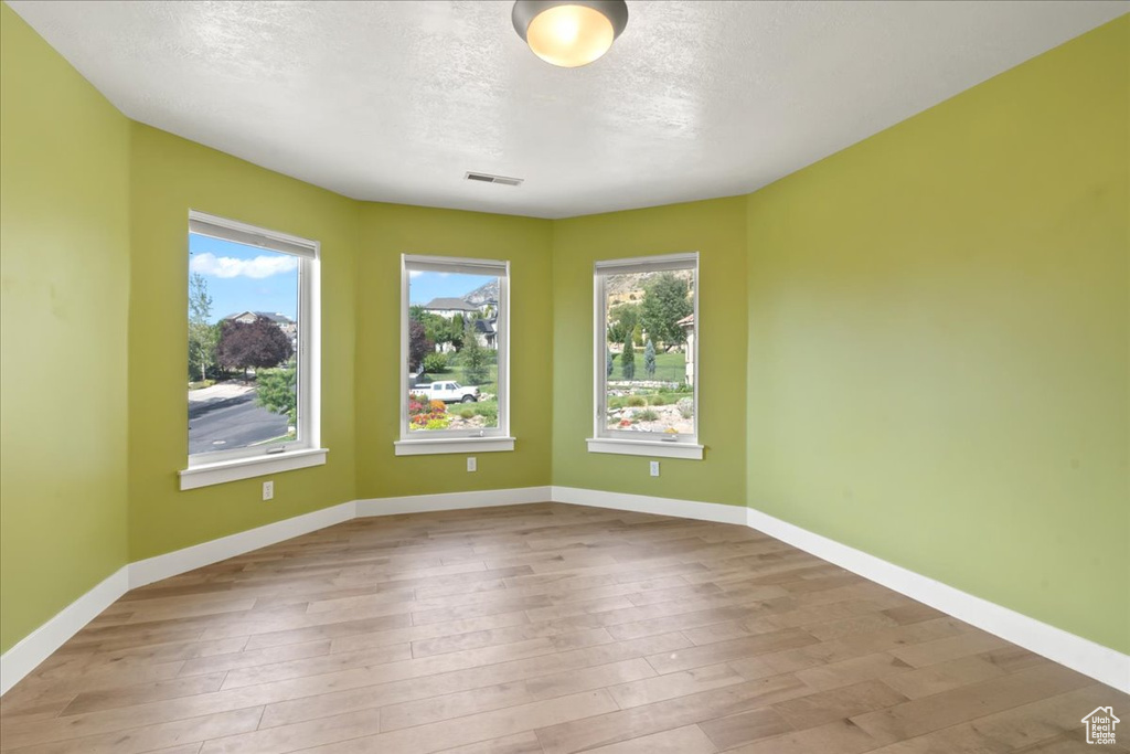 Spare room featuring a textured ceiling and light hardwood / wood-style floors