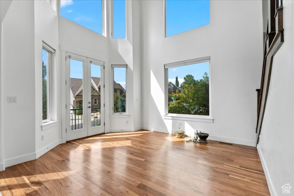 Unfurnished living room featuring hardwood / wood-style floors and a towering ceiling