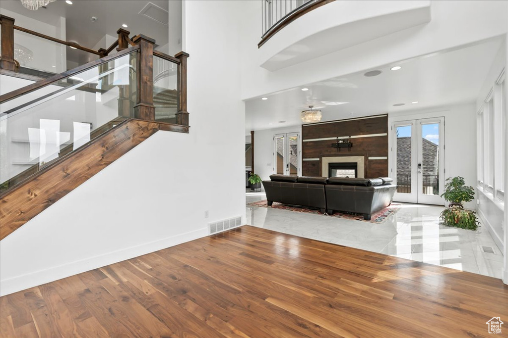 Living room with a fireplace, french doors, a towering ceiling, and hardwood / wood-style flooring