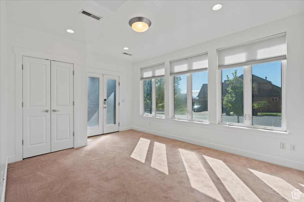 Unfurnished bedroom featuring light carpet and french doors