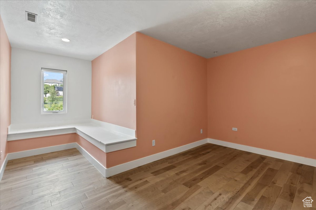 Additional living space featuring light wood-type flooring and a textured ceiling