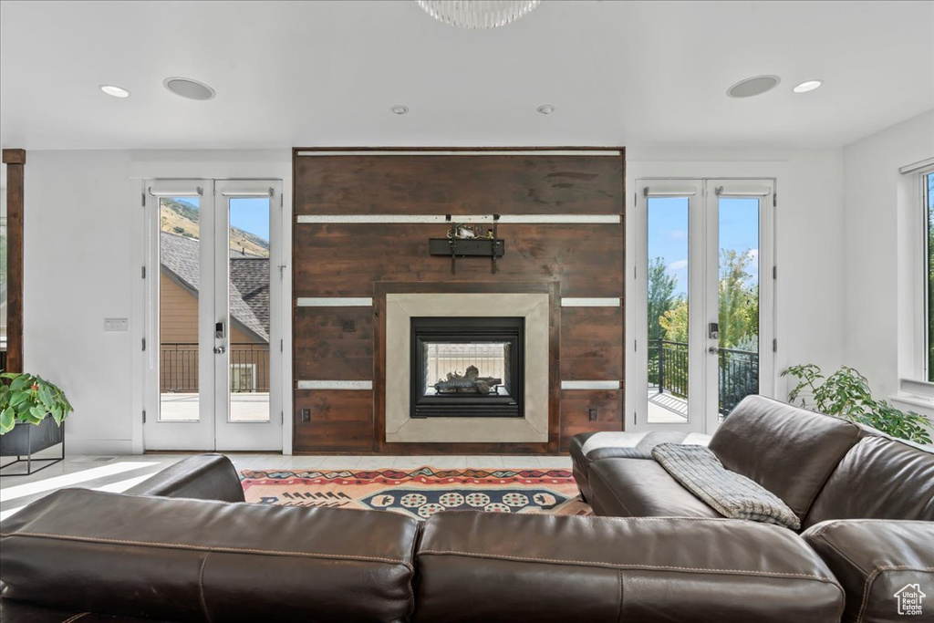 Living room with a healthy amount of sunlight, a multi sided fireplace, and french doors