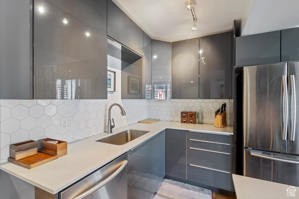 Kitchen featuring gray cabinetry, appliances with stainless steel finishes, backsplash, and sink