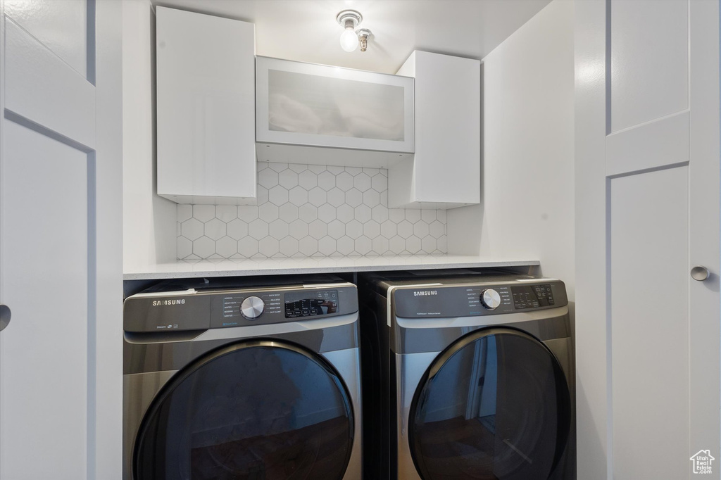 Clothes washing area featuring washer and dryer and cabinets