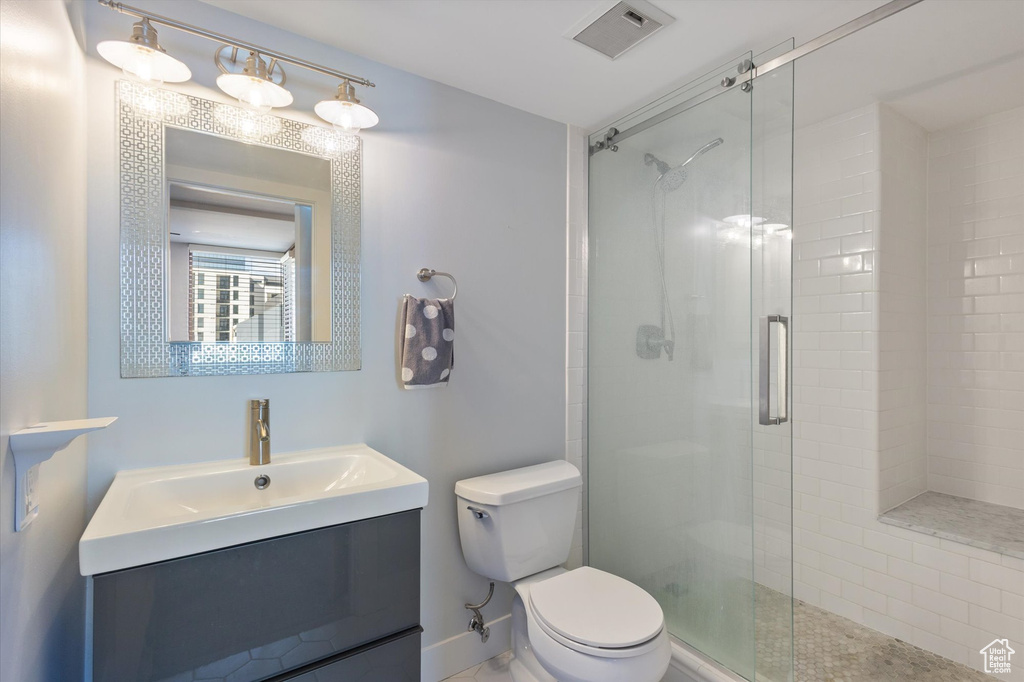 Bathroom featuring an enclosed shower, toilet, and vanity