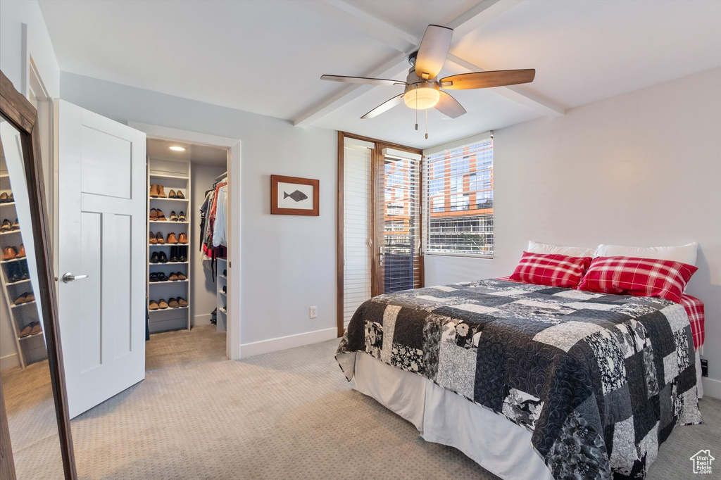 Carpeted bedroom featuring beam ceiling and ceiling fan