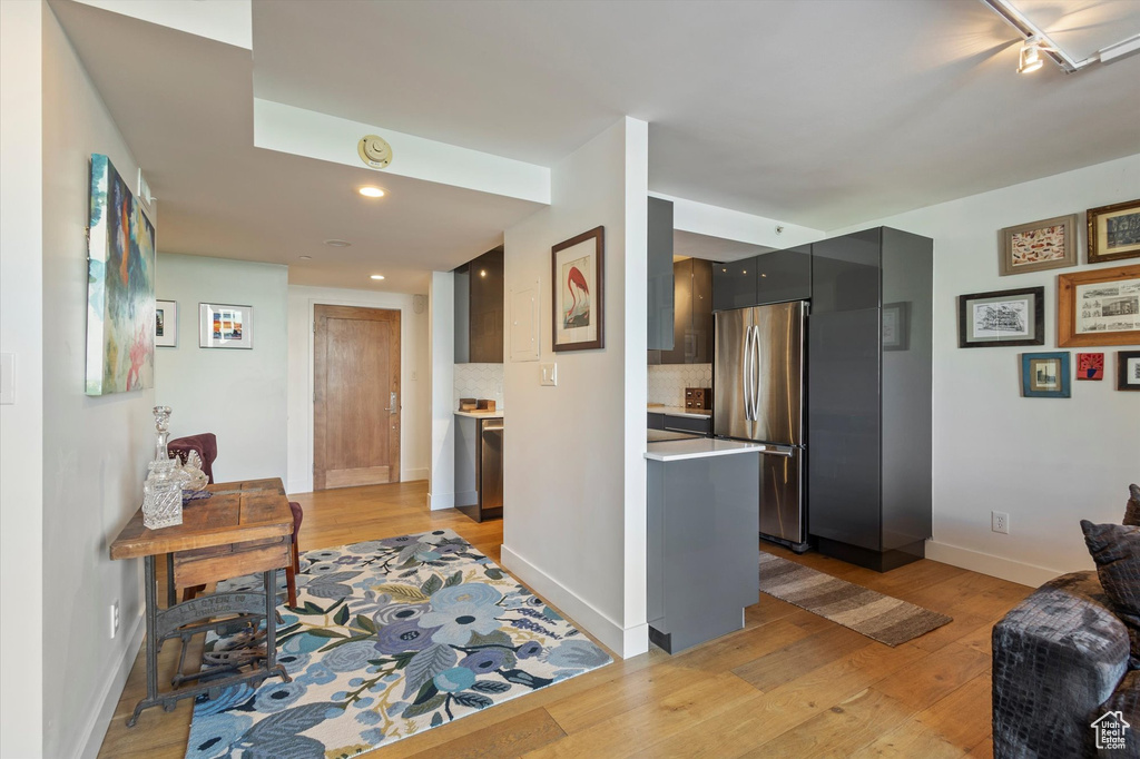 Kitchen featuring light wood-type flooring, stainless steel fridge, and decorative backsplash