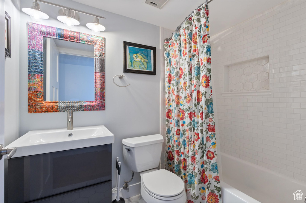 Full bathroom with vanity, toilet, and shower / bath combo with shower curtain