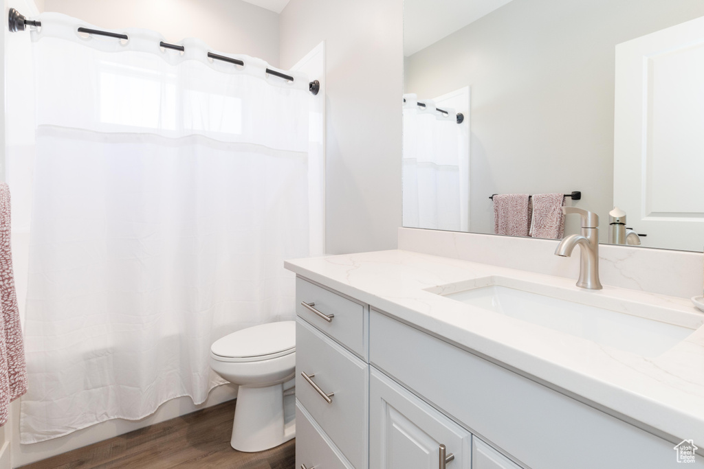 Full bathroom featuring hardwood / wood-style floors, vanity, toilet, and shower / bathtub combination with curtain