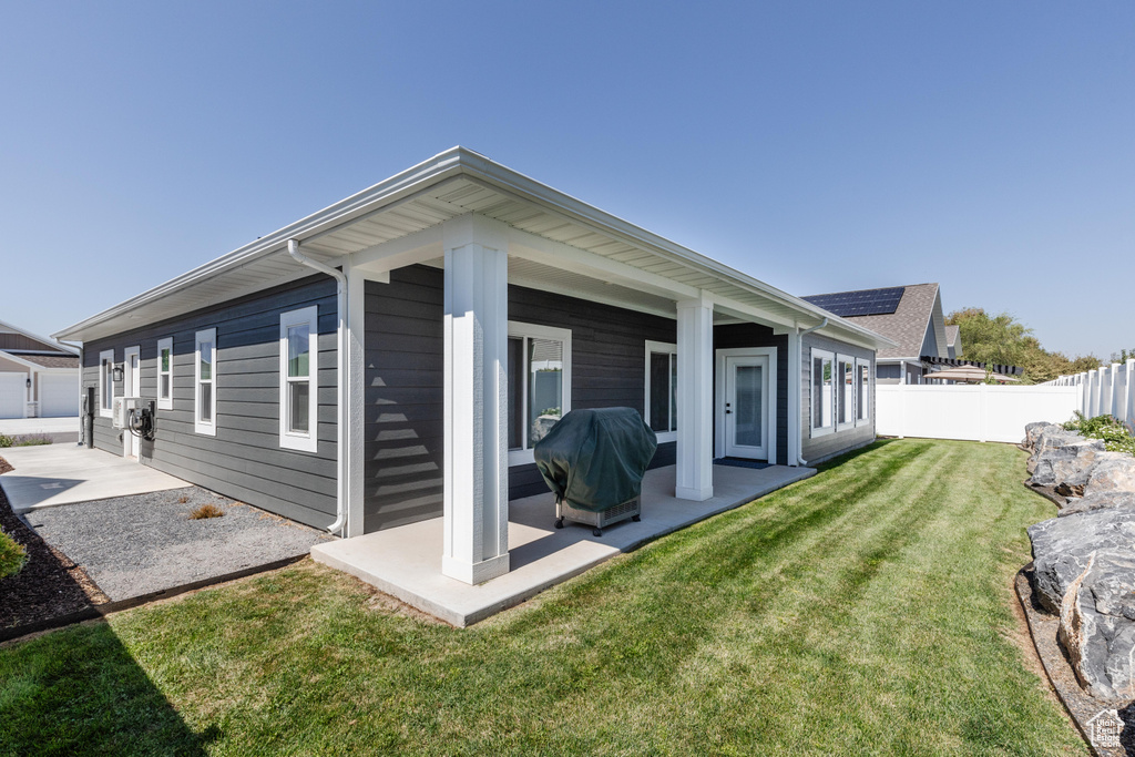 Rear view of house with a lawn and a patio