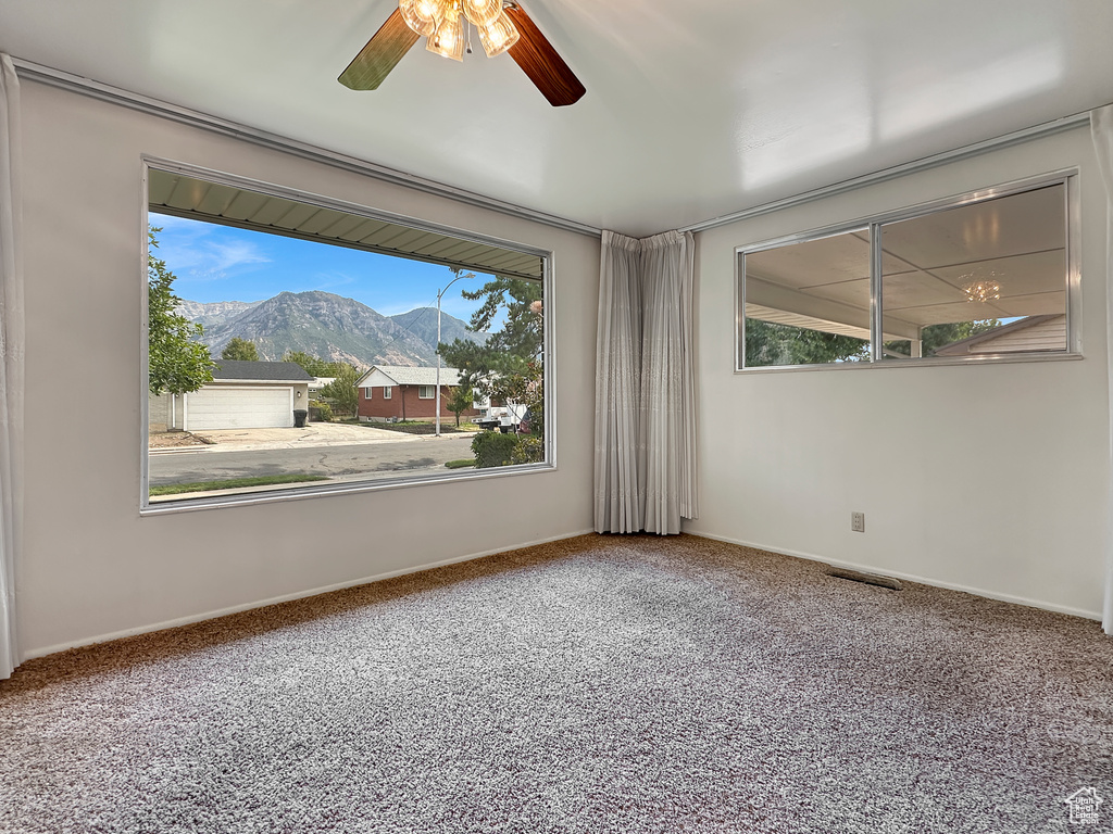 Carpeted spare room with a wealth of natural light, ceiling fan, and a mountain view